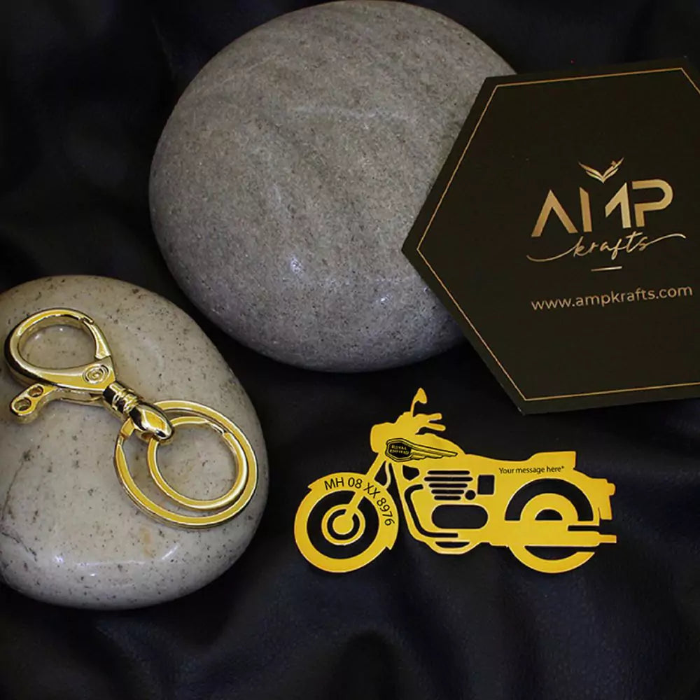 Gold motorcycle keychain and logo on a stone surface with 'AMP crafts' branding.